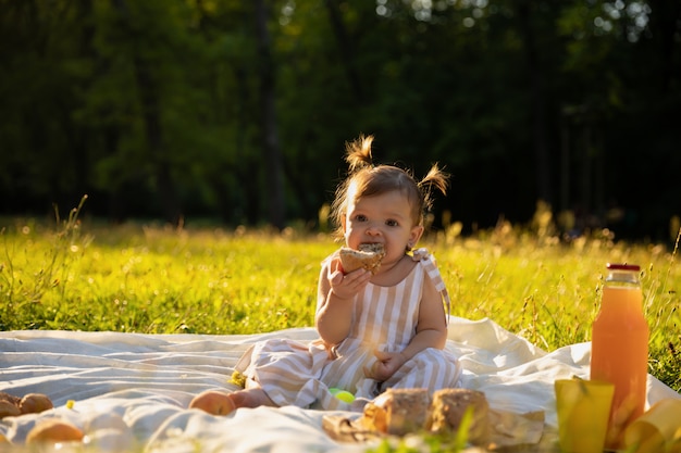 Bambina in un vestito a strisce su un picnic in un parco cittadino.