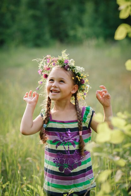 bambina in una corona di fiori selvatici in estate