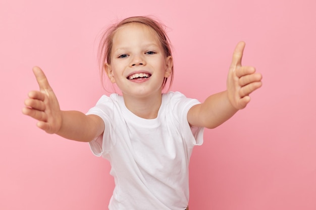 Bambina in una maglietta bianca sorriso sfondo rosa