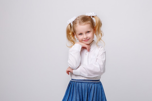 Bambina in uniforme scolastico su fondo bianco che legge un libro