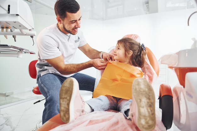 Bambina in visita dentista maschio in clinica Concezione di stomatologia