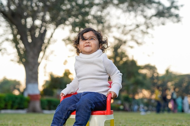 Bambina indiana o ragazzo seduto su una sedia in giardino