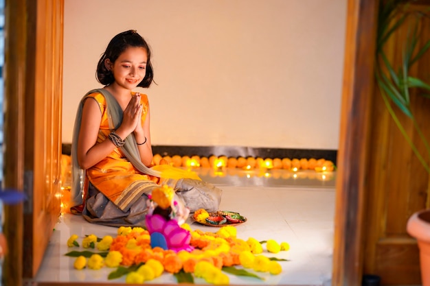 Bambina indiana sveglia che prega e celebra il festival di diwali.