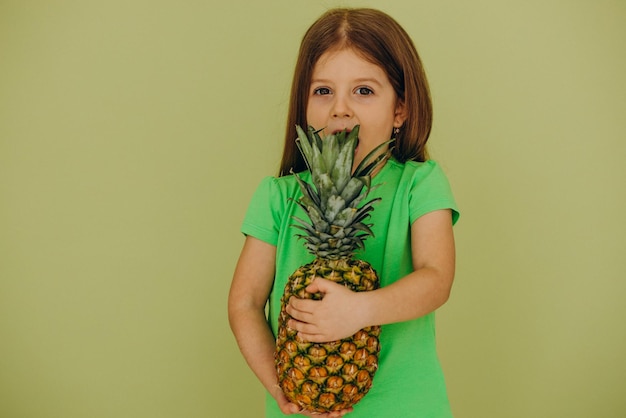 Bambina isolata che tiene ananas