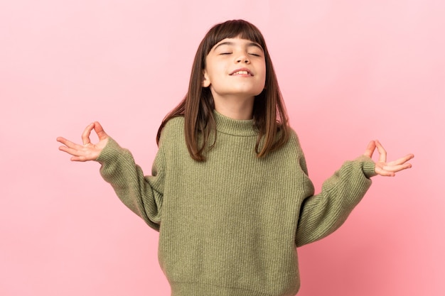 Bambina isolata su sfondo rosa in posa zen