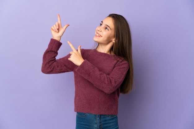 Bambina isolata su sfondo viola che indica con il dito indice una grande idea