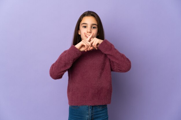 Bambina isolata su sfondo viola che mostra un segno di gesto di silenzio