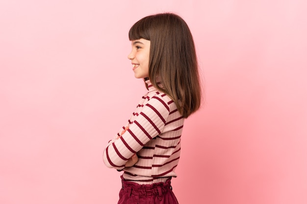 Bambina isolata sulla parete rosa in posizione laterale