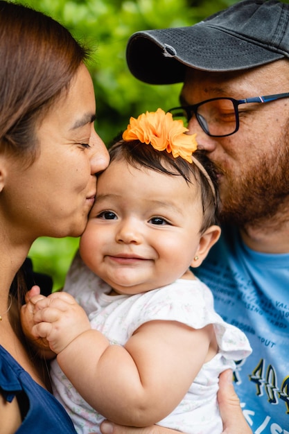 Bambina latina baciata da sua madre e suo padre latini