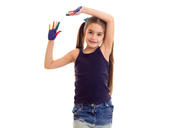 Bambina meravigliosa in camicia nera con due code di cavallo e mani colorate in studio
