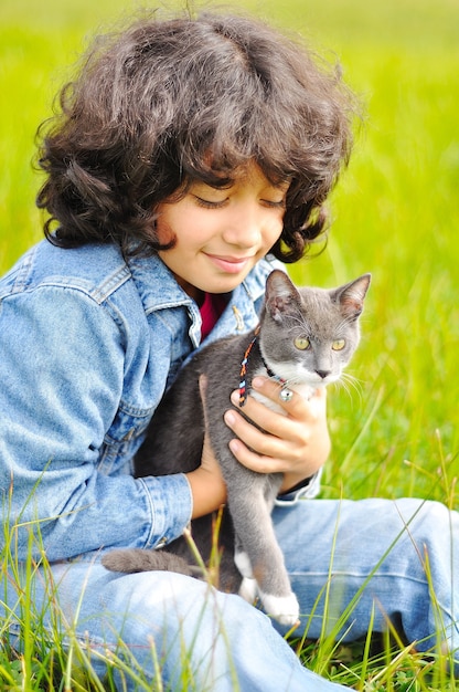 Bambina molto carina con gatto sul prato