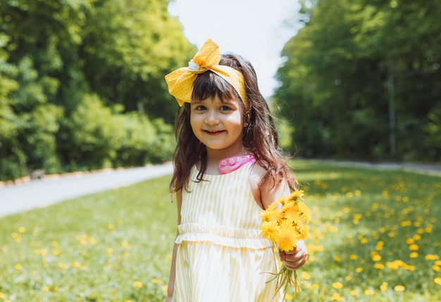 Bambina nel parco che raccoglie fiori gialli di tarassaco in una soleggiata giornata estiva