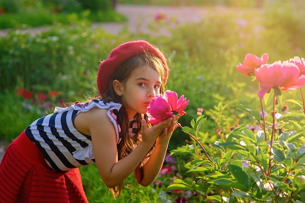 Bambina nel parco con in mano una grande peonia rosa