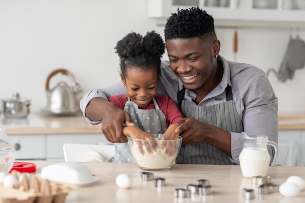 Bambina nera allegra che cucina con il suo papà