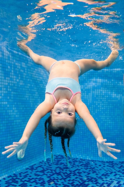 Bambina nuota sott'acqua nella piscina per bambini Immersioni Imparare a nuotare bambino Divertiti a nuotare e bubl