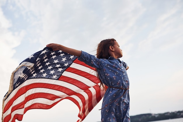 Bambina patriottica con bandiera americana in mano