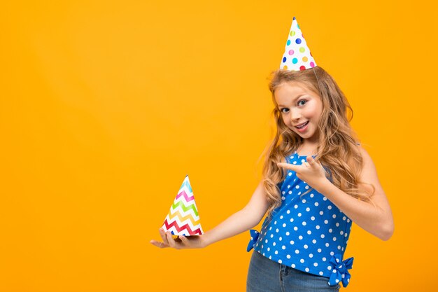 Bambina piacevole con una festa di compleanno isolata su bianco