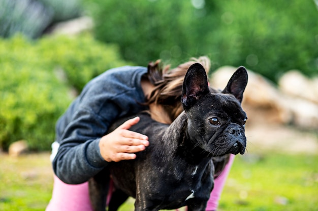 Bambina proteggente del bulldog francese in un parco