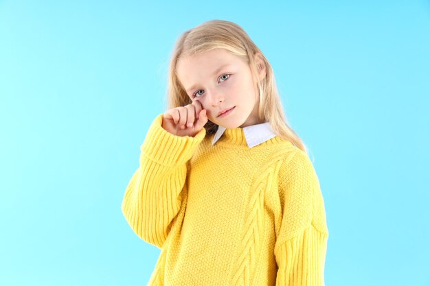 Bambina risentita in maglione su sfondo blu