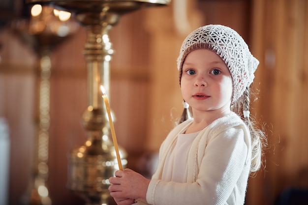 Bambina russa in una sciarpa sulla sua testa si trova in una chiesa ortodossa