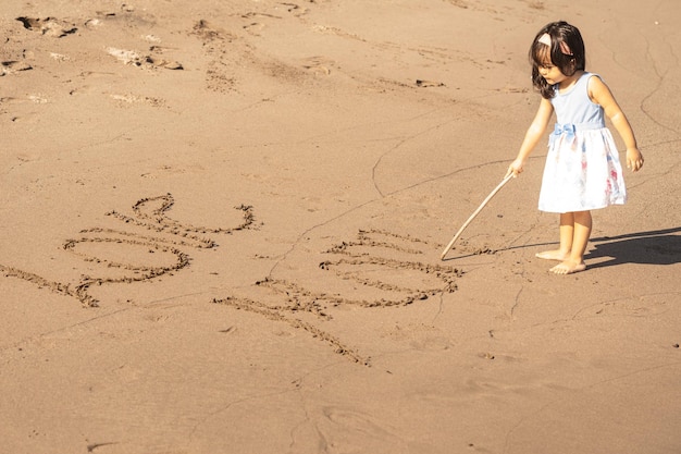 Bambina scrivendo quotti amo mammaquot nella sabbia su una spiaggia