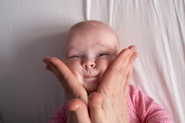 Bambina sdraiata madre mano premendo le guance e la testa