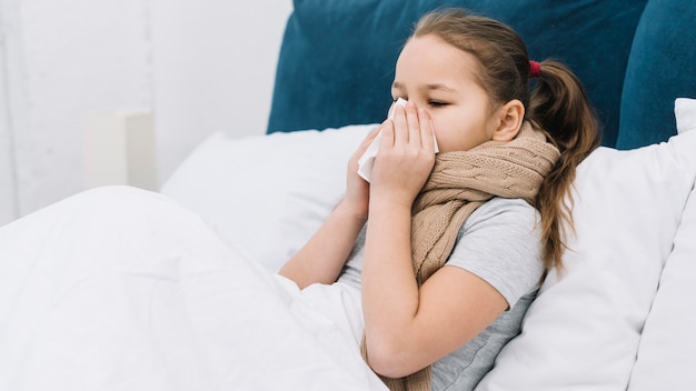 Bambina sdraiata sul letto soffre il freddo e la tosse