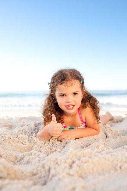 Bambina sdraiata sulla spiaggia