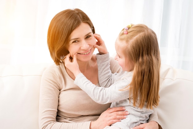 Bambina seduta con la mamma e fare facce buffe