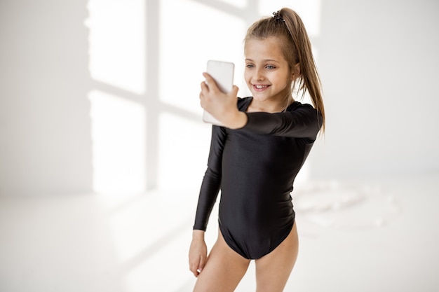 Bambina seduta con smart phone in classe di ginnastica