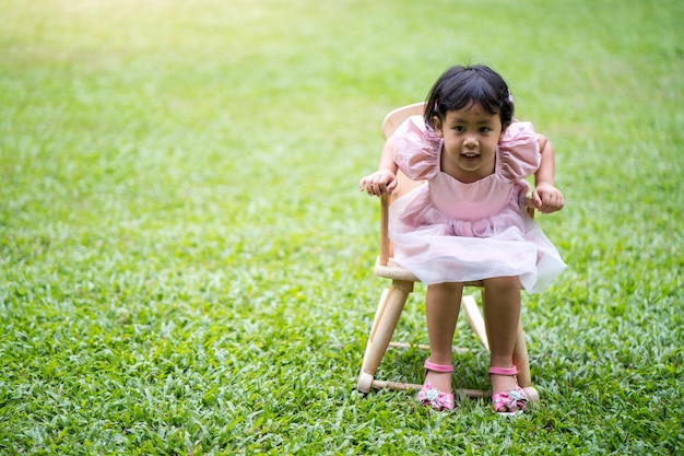 Bambina seduta su una sedia sull'erba