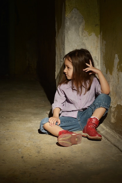 Bambina sola in una cantina buia