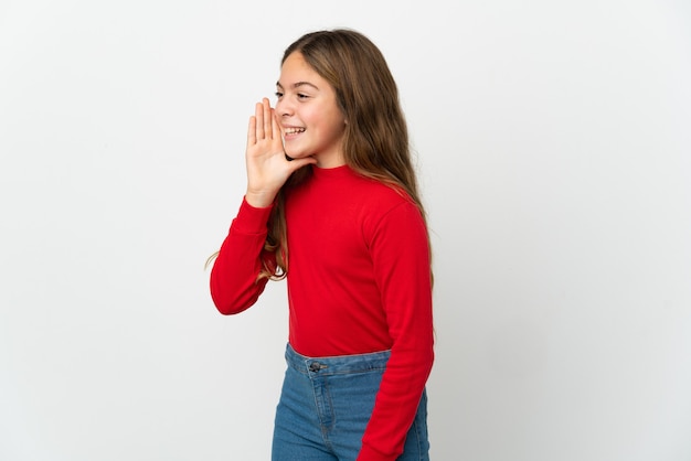 Bambina sopra fondo bianco isolato che grida con la bocca spalancata al lato