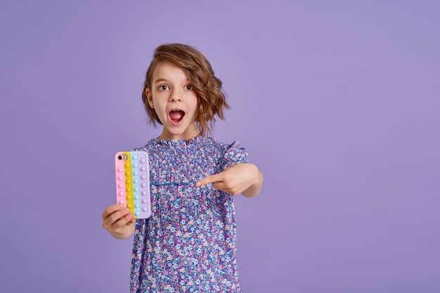 Bambina sorpresa che tiene telefono con la bocca aperta isolata sul viola