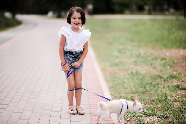 Bambina sorridente che cammina con un animale domestico di chihuahua nel parco