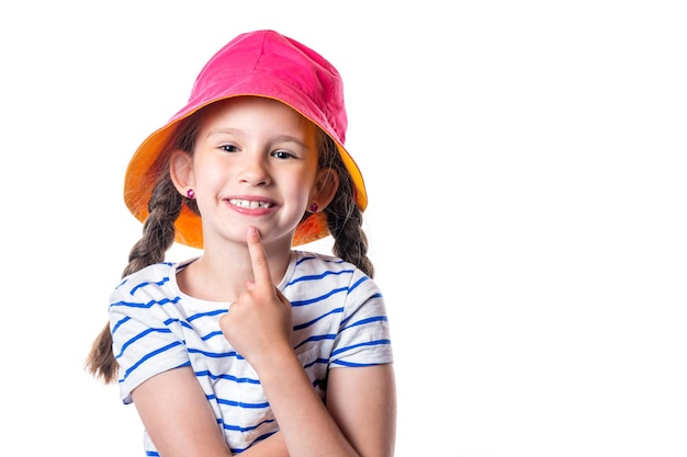 Bambina sorridente europea sveglia con il cappello rosa e le trecce isolate su fondo bianco.