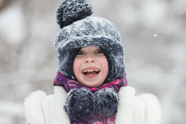 Bambina sorridente in giacca rosa nella foresta invernale