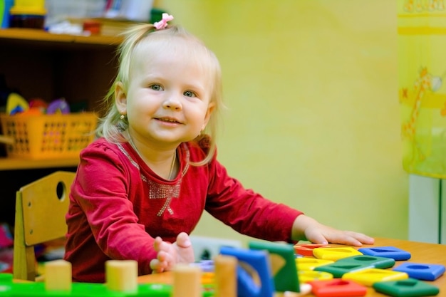 Bambina sorridente seduta a una scrivania in una lezione di sviluppo. Insegnamento dell'educazione scolastica. Classi colorate.