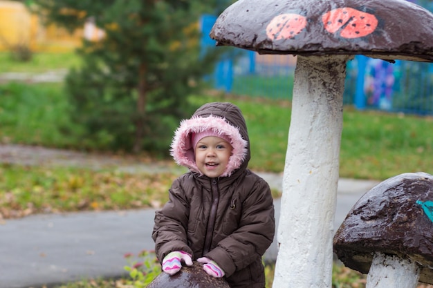 Bambina sorridente sveglia che guarda l'obbiettivo nel parco d'autunno