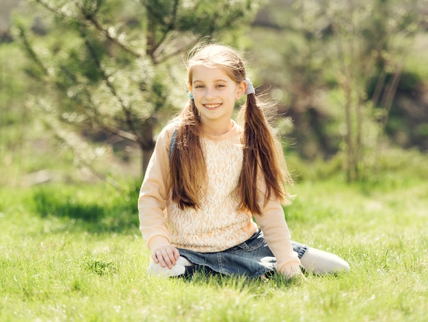 Bambina sorridente sveglia che si siede sull'erba