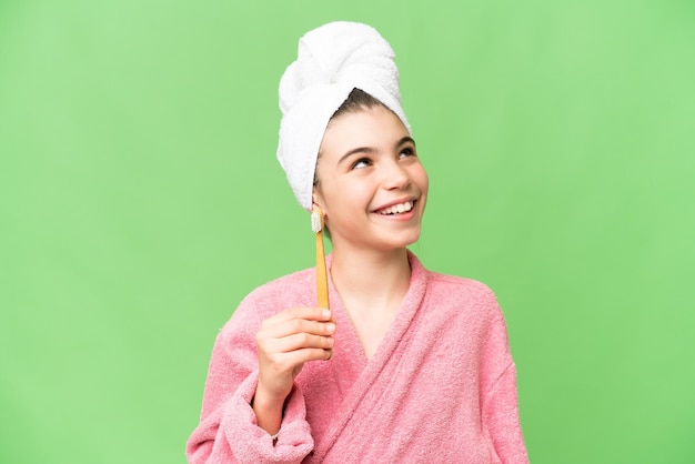 Bambina spazzolare i denti su sfondo chroma key isolato cercando mentre sorridente