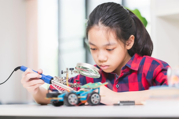 Bambina studente costruisce auto robotiche bambino impara a programmare veicoli robotici