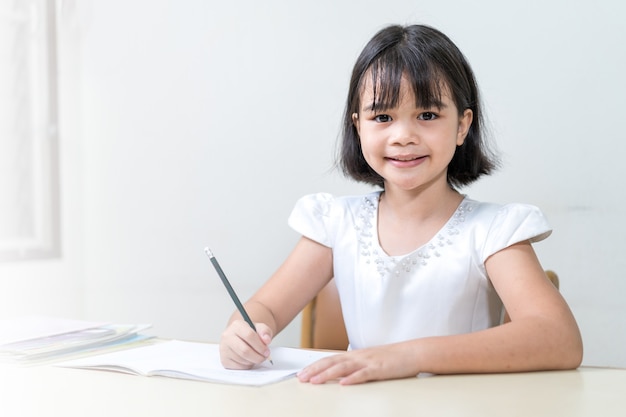 Bambina studentessa che scrive sul taccuino facendo i compiti e lo studio autonomo a casa