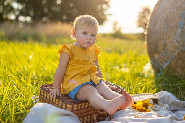 Bambina su un picnic alle luci del tramonto in natura