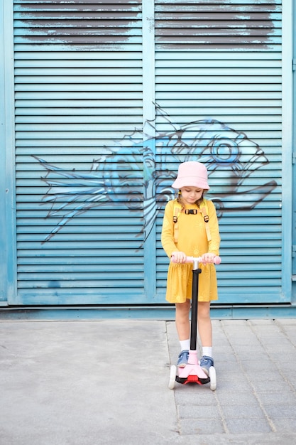 bambina su uno scooter contro il muro urbano