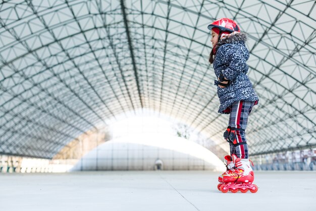 bambina sui rollerblade sulla pista di pattinaggio