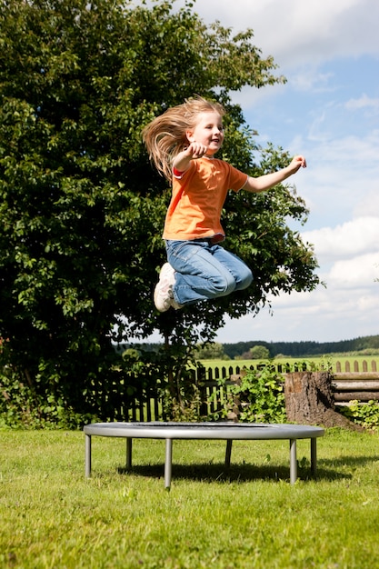 Bambina sul trampolino in giardino