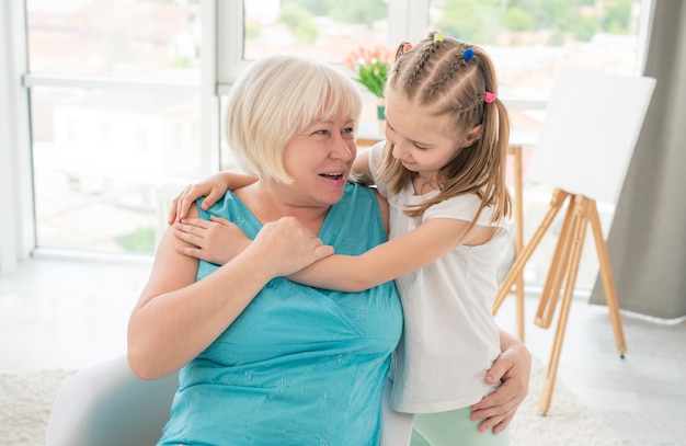 Bambina sveglia che abbraccia la nonna sorridente