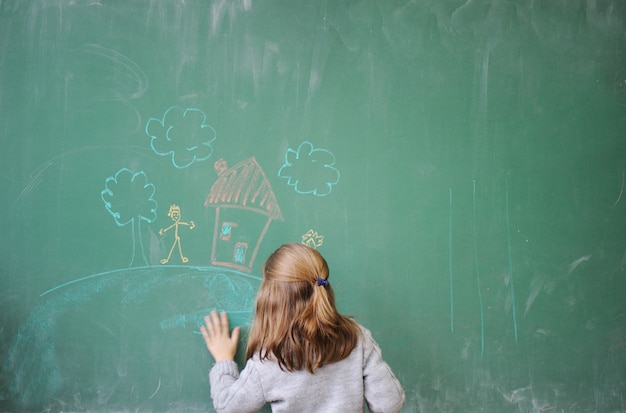 Bambina sveglia che attinge lavagna