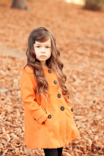 Bambina sveglia che cammina all'aperto Indossando un elegante cappotto autunnale nel parco esterno